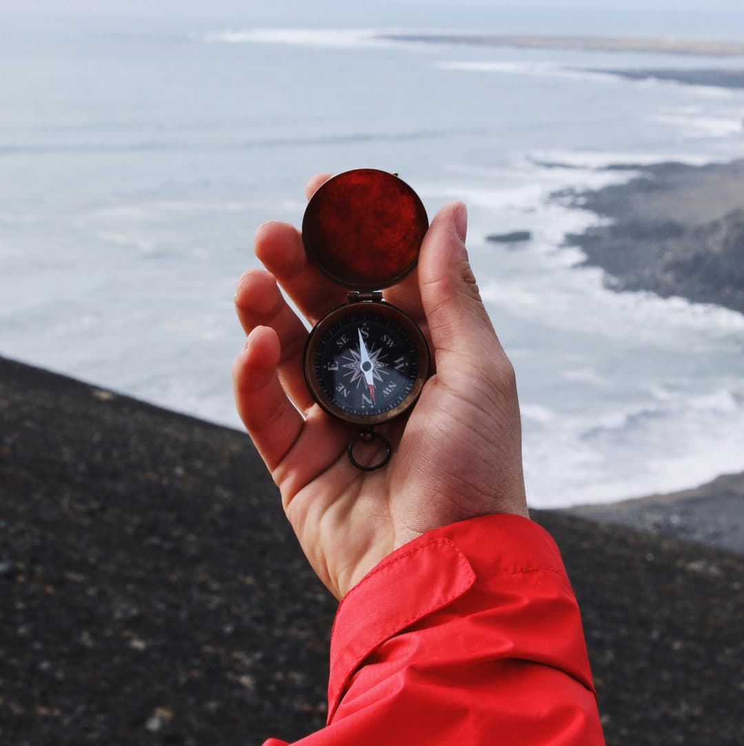 A hand holding a compass